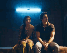 a man and a woman are sitting next to each other in front of a blue light