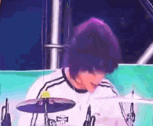 a person with purple hair is playing drums in a band