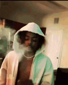 a shirtless man in a white hoodie is smoking a cigarette .