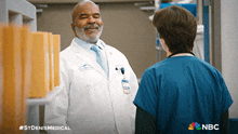 a man in a white lab coat is talking to a nurse with the nbc logo on the bottom