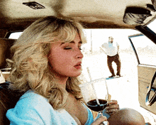 a woman is sitting in a car with a glass of wine