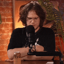 a man sitting in front of a microphone next to a can of cola
