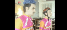 a man with a mohawk wearing a helmet and a pink and orange shirt that says ' good day ' on it