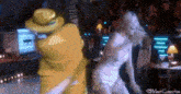 a woman in a white dress is dancing with a yellow masked man in a yellow suit .