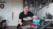 a man sitting at a desk with a sony laptop and a box of dvds