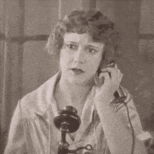a woman is talking on a telephone with a serious look on her face