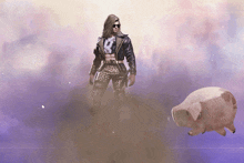 a man in a leather jacket stands next to a pig that is flying in the air