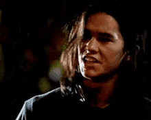 a close up of a man with long hair looking down at something .
