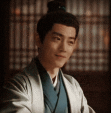 a man with a bun on his head is wearing a kimono and smiling .