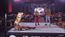 a wrestling ring with a sign that says rebellion in the background