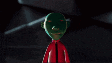 a cartoon character with a green face is smiling in front of a red background