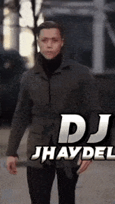 a man wearing a jacket and a turtleneck is standing in front of a sign that says dj jhayda