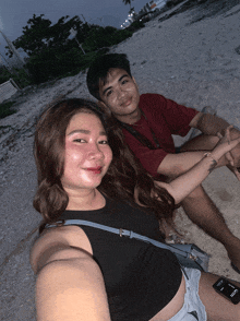 a man and a woman sitting on a beach with a phone that says samsung