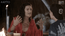 a woman in a red top is talking to a man in a black hat with the word ayto on it