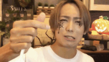 a man with a spider web tattoo on his face is holding a lollipop in his hand .