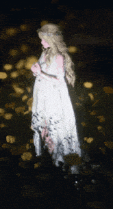 a woman in a white dress is standing in a field of yellow flowers