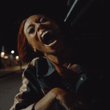 a woman is screaming with her mouth open in a dark room