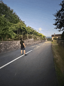 a person riding a skateboard down a road with trees on the side