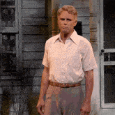 a man in a white shirt and brown belt stands in front of a door