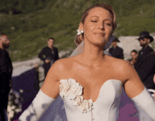 a woman in a white wedding dress with a flower on the side