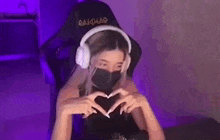 a woman wearing headphones and a mask is sitting in a chair in a room .