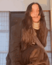 a woman with long hair is standing in front of a window