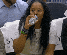 a woman is drinking water from a bottle in front of a seat that says sy