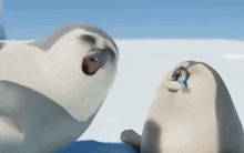 two seals are sitting on top of a snow covered surface .