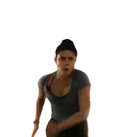 a woman in a gray shirt and black jeans is making a funny face