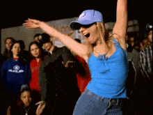 a woman in a blue tank top is dancing in front of a crowd .