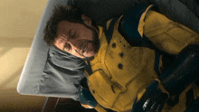 a man in a yellow and blue superhero suit is laying on a bed