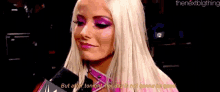a woman with blonde hair and pink makeup is holding a microphone and talking into it .
