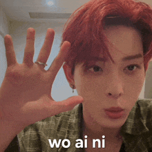 a young man with red hair is wearing a plaid shirt and a ring on his finger and says wo ai ni
