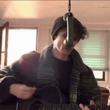 a man playing an acoustic guitar with a microphone hanging from the ceiling