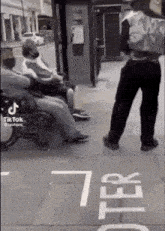 a man is standing in front of a group of people sitting on a bench .