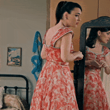 a woman in a red dress is looking at her reflection in a mirror