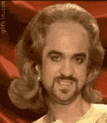 a man with long hair and a beard is wearing a woman 's wig .
