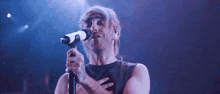 a man singing into a microphone with his hand on his heart