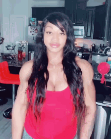 a woman in a red tank top is standing in front of a kitchen