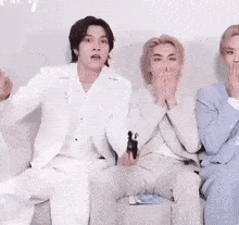 a group of men in suits are sitting on a couch .