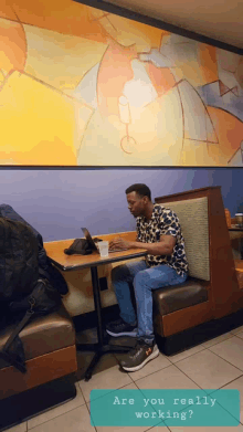 a man sits at a booth in a diner using a tablet computer
