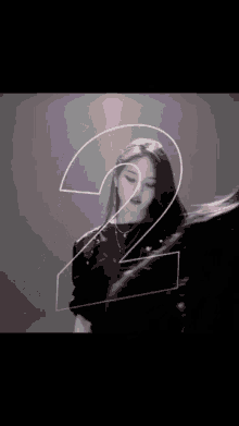 a woman is standing in front of a large number 2 .