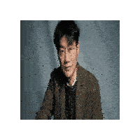a man in a suit and glasses is sitting in front of a blue background .