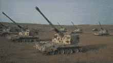 a row of military tanks in a desert with one that says ' aa ' on the side of it