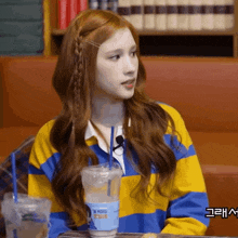 a woman sitting at a table with a cup that has a straw in it