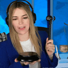 a woman wearing headphones and a blue jacket is holding a microphone