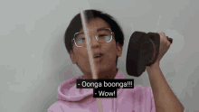 a man wearing glasses and a pink hoodie is holding a dumbbell and saying oonga boonga wow