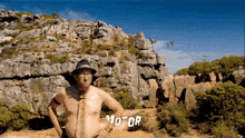 a man without a shirt is standing in front of a mountain and the word motor is on the bottom