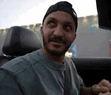 a man with a beard is sitting in the back seat of a car looking at the camera .