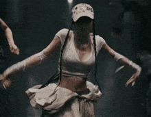 a woman wearing a hat with flowers on it is dancing in a dark room